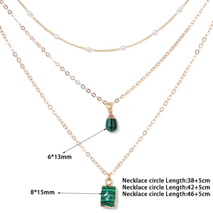 Detailed view of 18k gold triple-layered necklace with natural green stone and pearl charms
