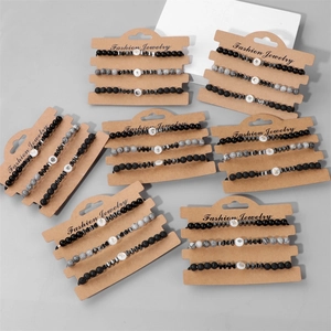Set di tre braccialetti con perle in pietra lavica e conchiglia su espositore