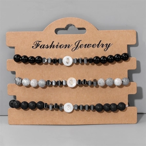 Set di tre braccialetti in perline di pietra lavica e conchiglia su cartoncino espositivo