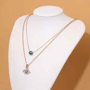 Detail view of double-layer evil eye pendant necklace with crystals on a white bust stand