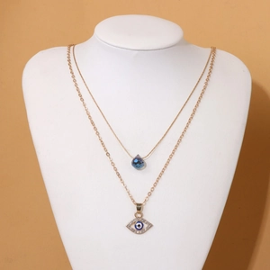 Double-layer gold necklace featuring a blue teardrop pendant and crystal Evil Eye charm