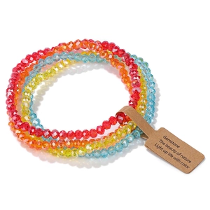Makroaufnahme bunter facettierter Glasperlen-Armbänder mit Kraftpapier-Geschenkanhänger