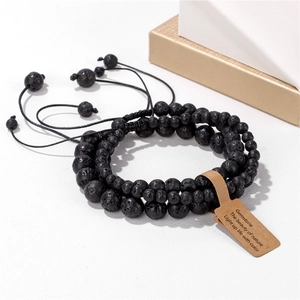 Macro detail of three-piece black lava stone beaded bracelets with adjustable woven cord