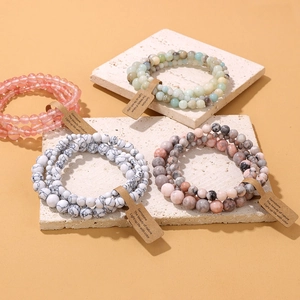 Detalle de pulseras de cuentas de piedra natural con etiquetas sobre bloques de travertino