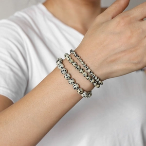 Detalle de tres pulseras de cuentas de jaspe dálmata en capas en la muñeca de un modelo