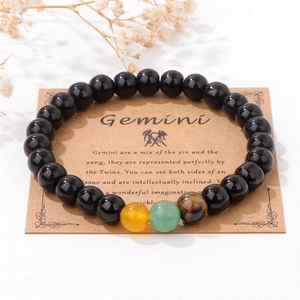 Dettaglio del bracciale zodiaco Gemelli su cartoncino marrone con perle nere lucide