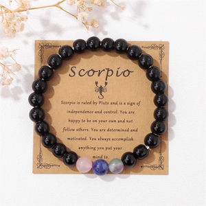 Dettaglio del bracciale di perle nere dello Scorpione su carta regalo con fiori secchi
