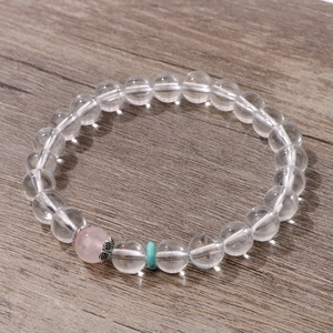 Primer plano de cuentas de cristal blanco de 8mm y piedra rosa sobre madera
