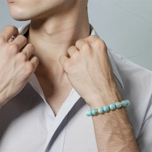 Bracelet pour homme en perles de pierre bleue avec entretoises dorées porté par un mannequin