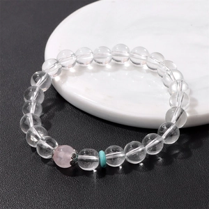 Pulsera minimalista de cuentas de cristal blanco y rosa en un soporte redondo
