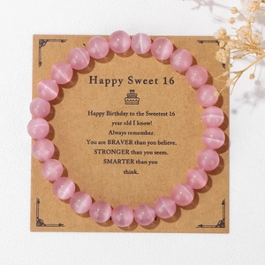 Detalle de pulsera de ojo de gato rosa sobre tarjeta de regalo de 16 años de cumpleaños