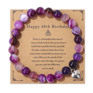 Détail d'un bracelet en perles d'agate violettes avec pendentif cœur sur carte d'anniversaire