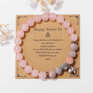 Détail d'un bracelet en quartz rose avec pendentif cœur sur une carte de 16e anniversaire