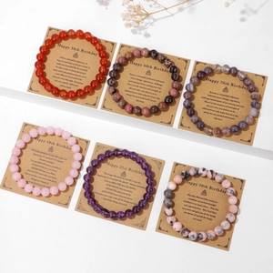 Detalle de seis pulseras de cuentas de piedra natural con tarjetas de cumpleaños kraft