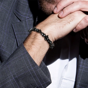 Bracelet pour homme en pierres noires naturelles porté avec un costume de ville élégant