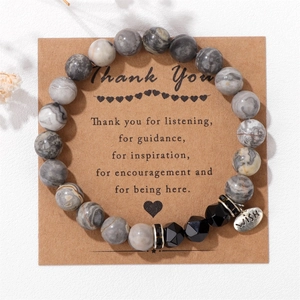 Detailed macro view of 8mm marble stone beads with a silver 'WISH' charm on kraft gift card