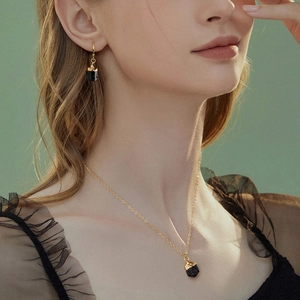 Parure collier et boucles d'oreilles dorés avec pierres noires sur un mannequin