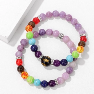 Detalle macro del conjunto de 2 pulseras chakra con cuentas púrpuras y grabado de mantra om