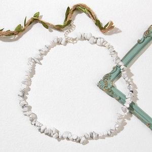 Détail de perles irrégulières en marbre blanc avec fermoir mousqueton argenté et chaîne