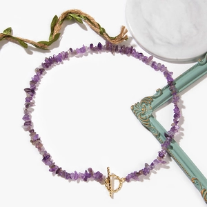 Detail shot of purple amethyst chip necklace with a gold OT toggle clasp on marble surface