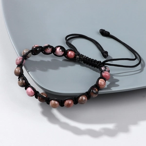 Dettaglio di perle di pietra da 6mm e cordino intrecciato nero su un piatto di ceramica