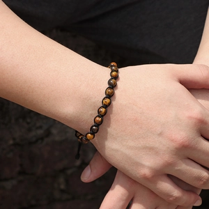 Dettaglio macro del bracciale in pietra occhio di tigre intrecciato a mano con trama dorata