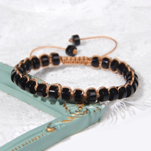 Detail van handgeweven armband met zwarte stenen kralen en verstelbaar bruin nylon koord