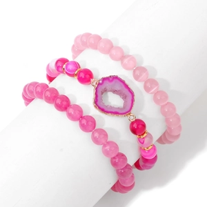 Détail macro de la tranche de géode rose et des bracelets en perles d'agate rayées