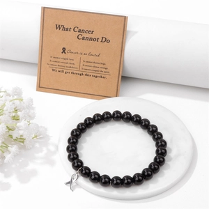 Schwarzes Perlenarmband mit silbernem Bandsymbol und Motivationskarte auf Marmorplatte
