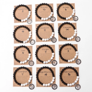 Matrix of 12 zodiac bracelets with black beads and silver charms on kraft cards
