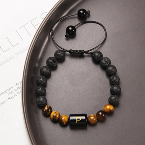 Bracciale in occhio di tigre e pietra lavica con lettera P su un vassoio grigio