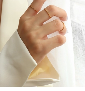 Three minimalist gold band rings worn on different finger joints of a model