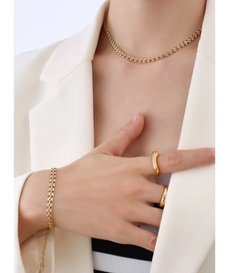 Détail d'un ensemble de bijoux dorés avec mailles tissées et larges bagues lisses