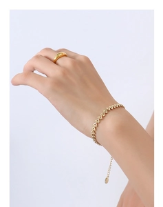 Gros plan sur le bracelet à maillons dorés et bague minimaliste polie assortie