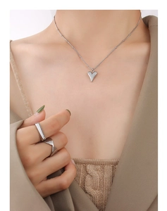 Detail showing heart pendant necklace and minimalist silver rings on model neck and fingers