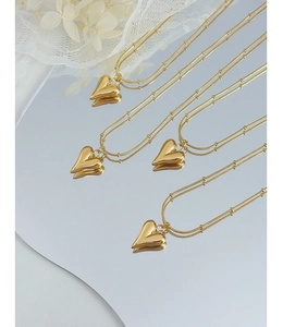 Detail showing 18K gold-plated double-layer heart pendant necklace on mirror