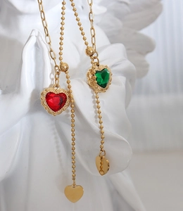 Detail of vintage heart pendants with red and green zircons and adjustable bead chain