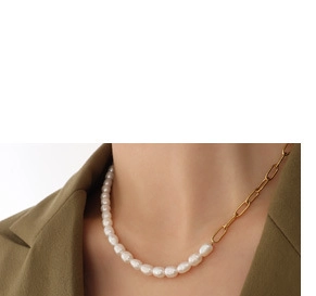 Détail d'un collier demi-perles et demi-chaîne trombone dorée sur un blazer