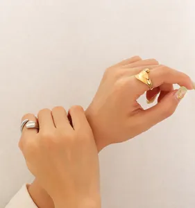 Detailopname van minimalistische gouden en zilveren ringen met golvend oppervlak op de vingers