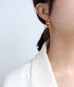 Nahaufnahme goldener Fransen-Kettenohrringe am Modell mit eleganten verschlungenen Metallringen