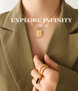 Detail of 18K gold-plated S-pendant necklace and rings styled with a green blazer