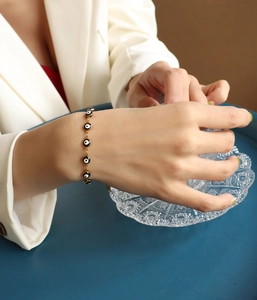 Detalle de modelo con pulsera de ojo turco dorado con dijes de esmalte en azul y negro