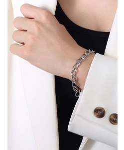Dettaglio di un bracciale a catena d'argento con grandi maglie rotonde al polso di una modella