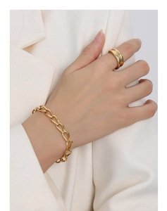 Dettaglio del bracciale a catena in oro 18k lucido e anello d'oro minimalista sul modello