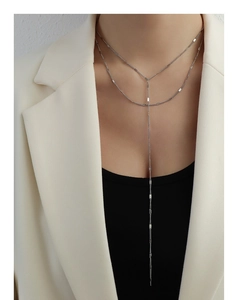 Detail of silver double-layered Y-shaped necklace with flat metal squares on model