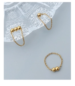 Détail de bagues en chaîne dorée avec billes polies dans un style minimaliste chic