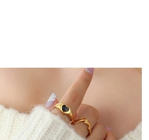 Gros plan sur bague chevalière cœur dorée et anneau ondulé avec pull blanc doux