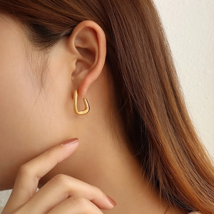 Elegante dikke U-vormige oorbellen in gepolijst 18K goud op een vrouwelijk model