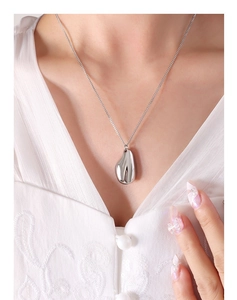 Gros plan d'un pendentif en métal liquide porté avec une blouse en dentelle