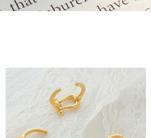 Macro shot of gold-plated U-shaped earrings with twisted texture on lace background